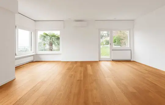 Terra de parquet de fusta natural en estança reformada amb finestrals i parets blanques