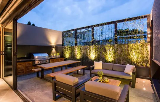 Jardí vertical integrat en terrassa reformada a Girona amb barbacoa d'obra i zona lounge