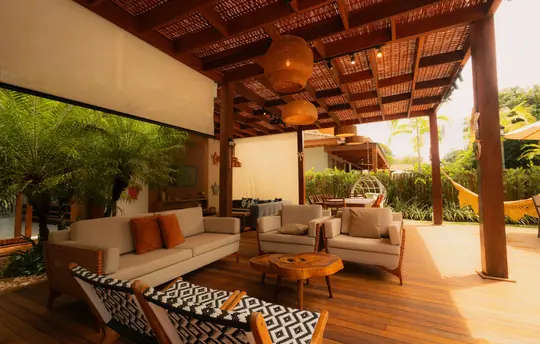 Terrassa tropical reformada amb sostre de fusta, hamaca i zona lounge amb butaques i sofà