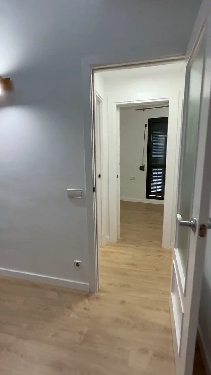 Habitació amb terra laminat clar i porta lacada en blanc