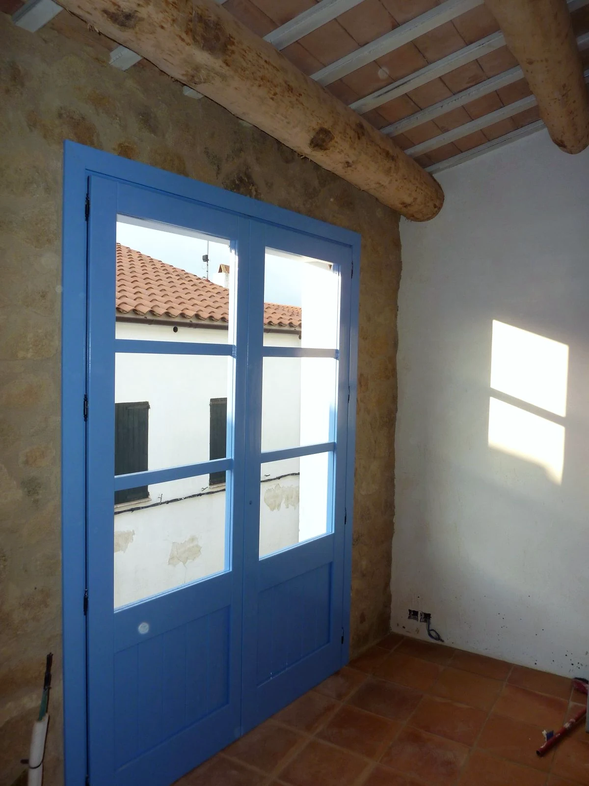 Balconera de fusta blava amb vistes a les teulades de Calella