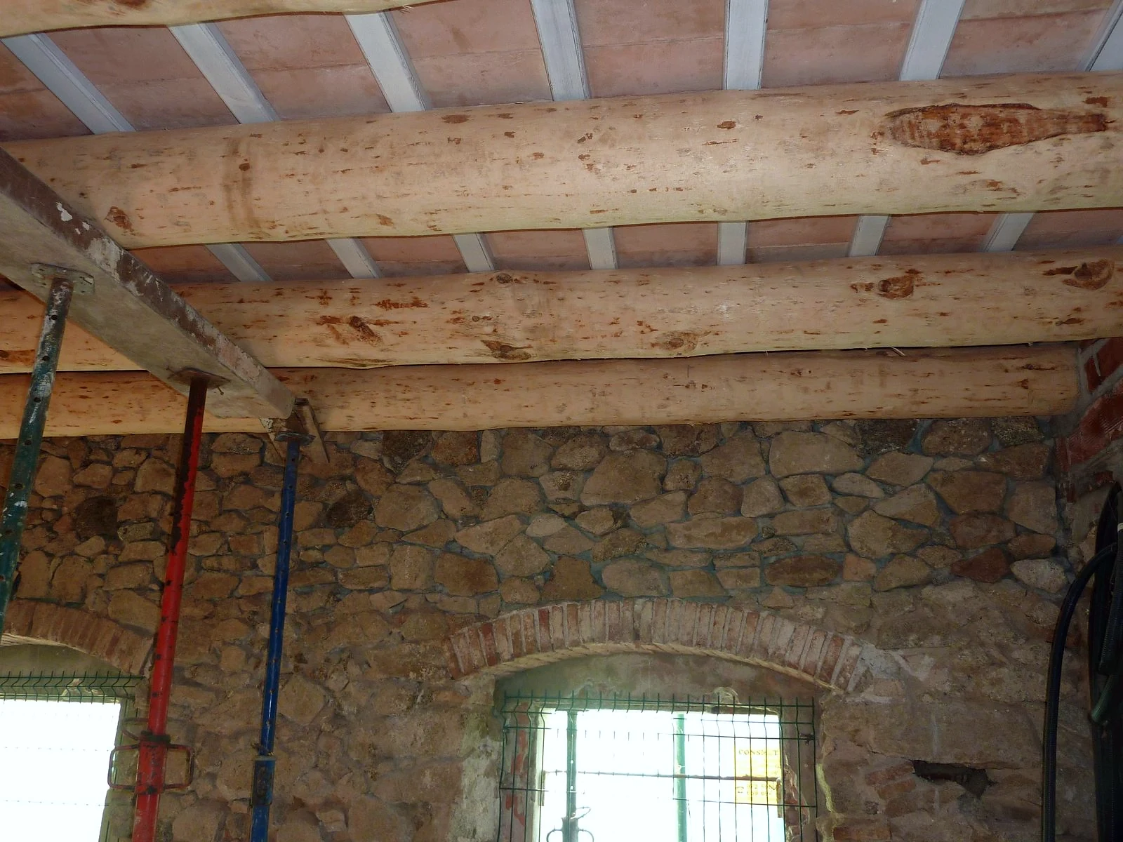 Forjat antic de bigues de fusta apuntalat i mur de pedra a l'inici de la reforma de la casa