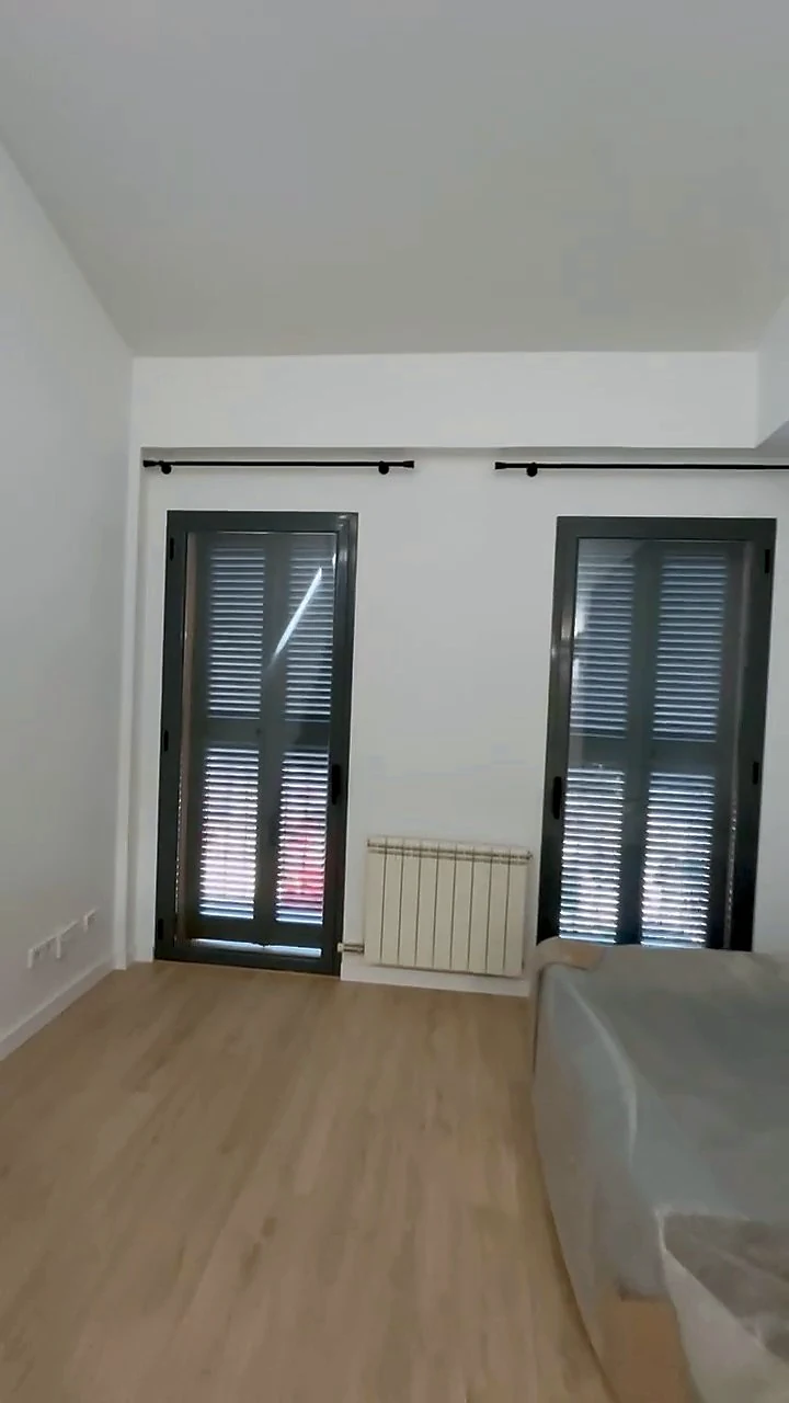 Sala del dúplex reformat amb terra laminat clar i dues balconeres