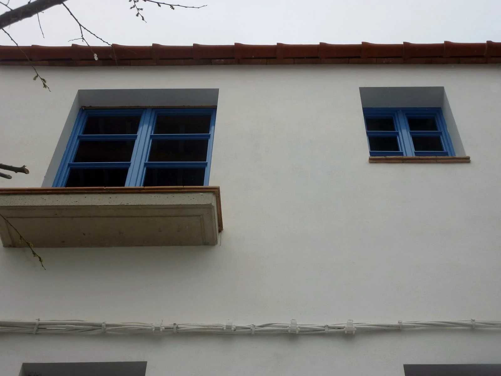 Detall de la façana blanca amb balcó i finestres blaves