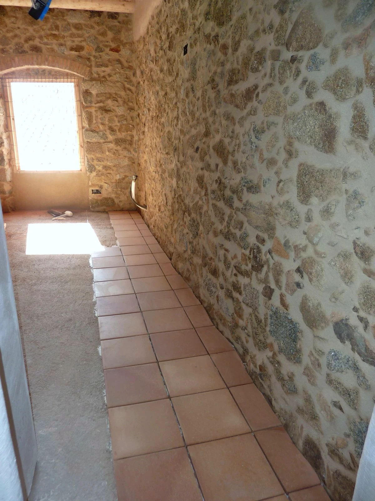 Passadís amb terra de terra cuita i mur de pedra vista